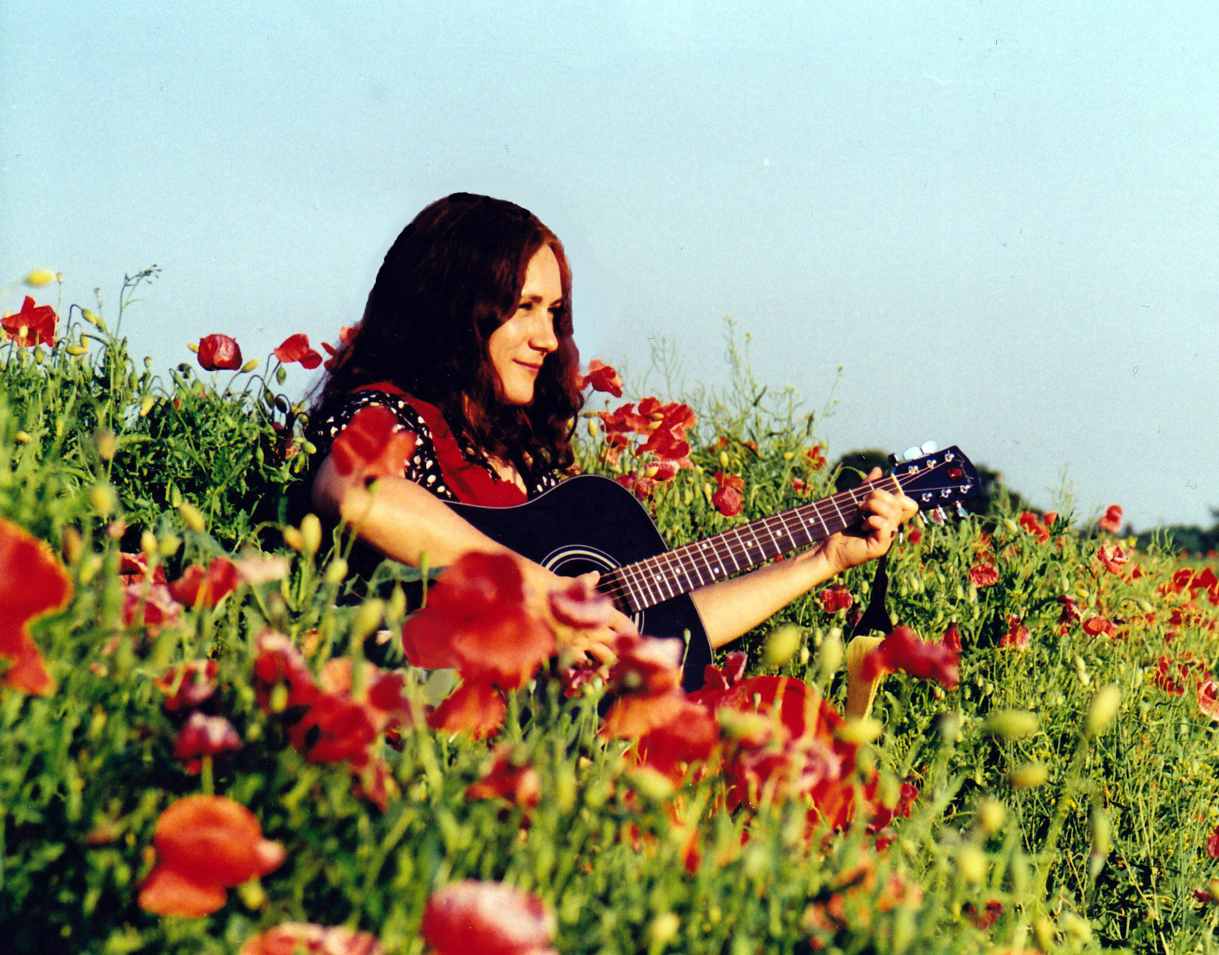 Martina Brück mit Gitarre in einem Mohnfeld